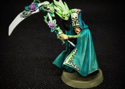 Miniatura de juego de rol pintada a mano: nigromante para HeroQuest con capa verde, guadaña y calaveras.